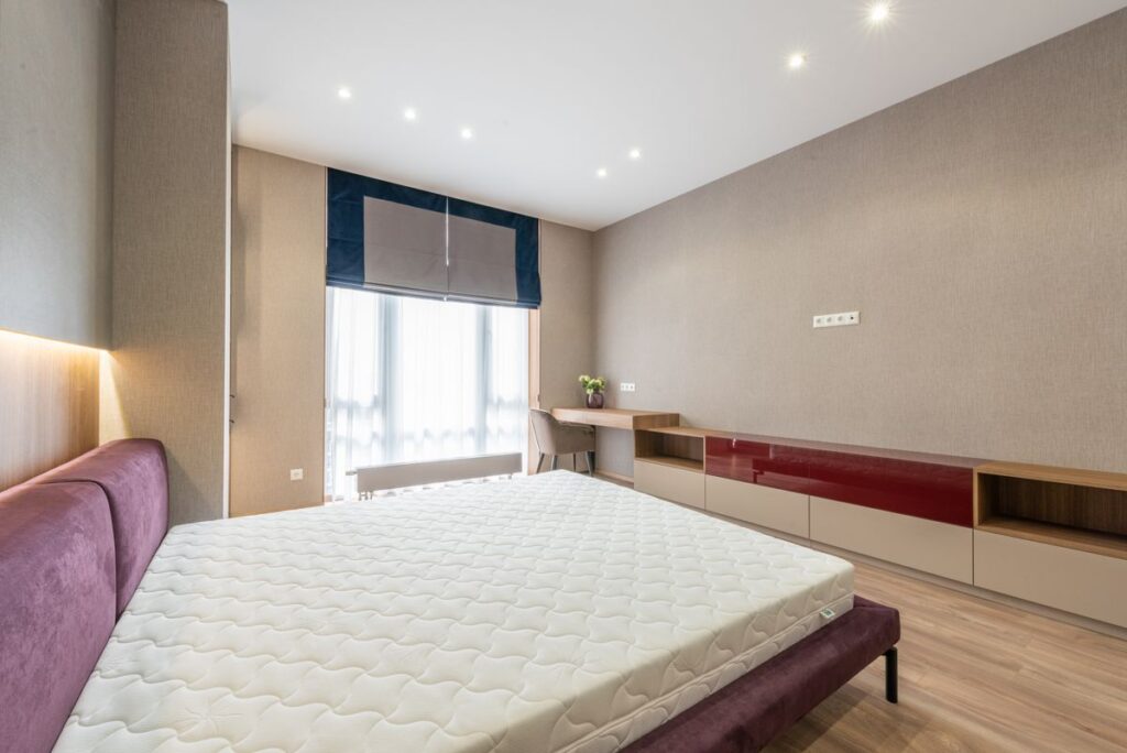 Full-size mattress on an upholstered bed in a bright modern bedroom