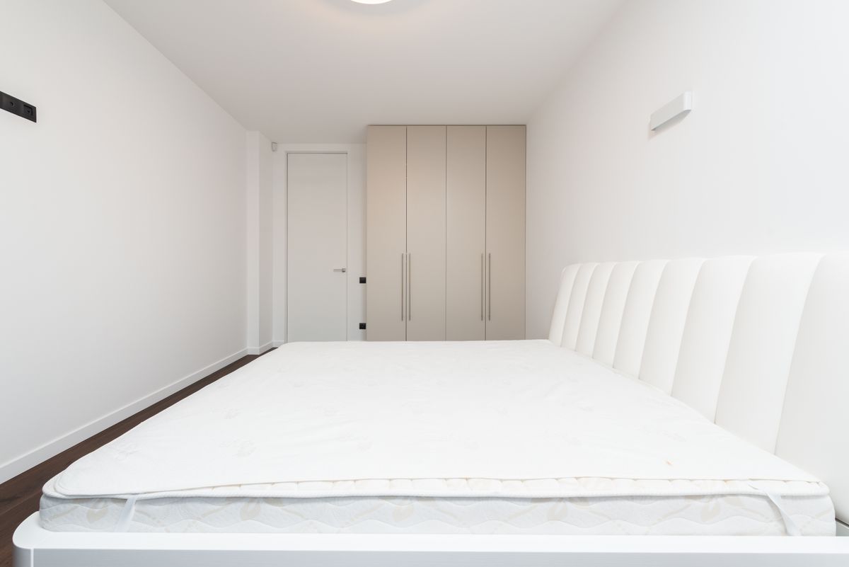 White mattress on a bed frame in a minimalist bedroom