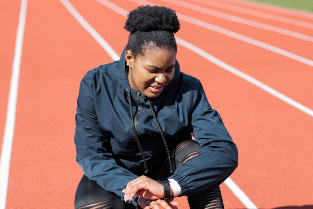 Runner checking her smartwatch on an athletics track