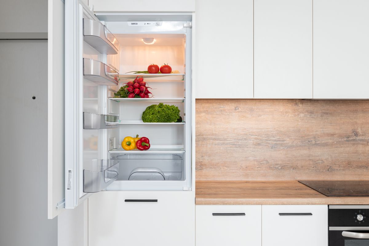 Refrigerador abierto con frutas y verduras en una cocina moderna