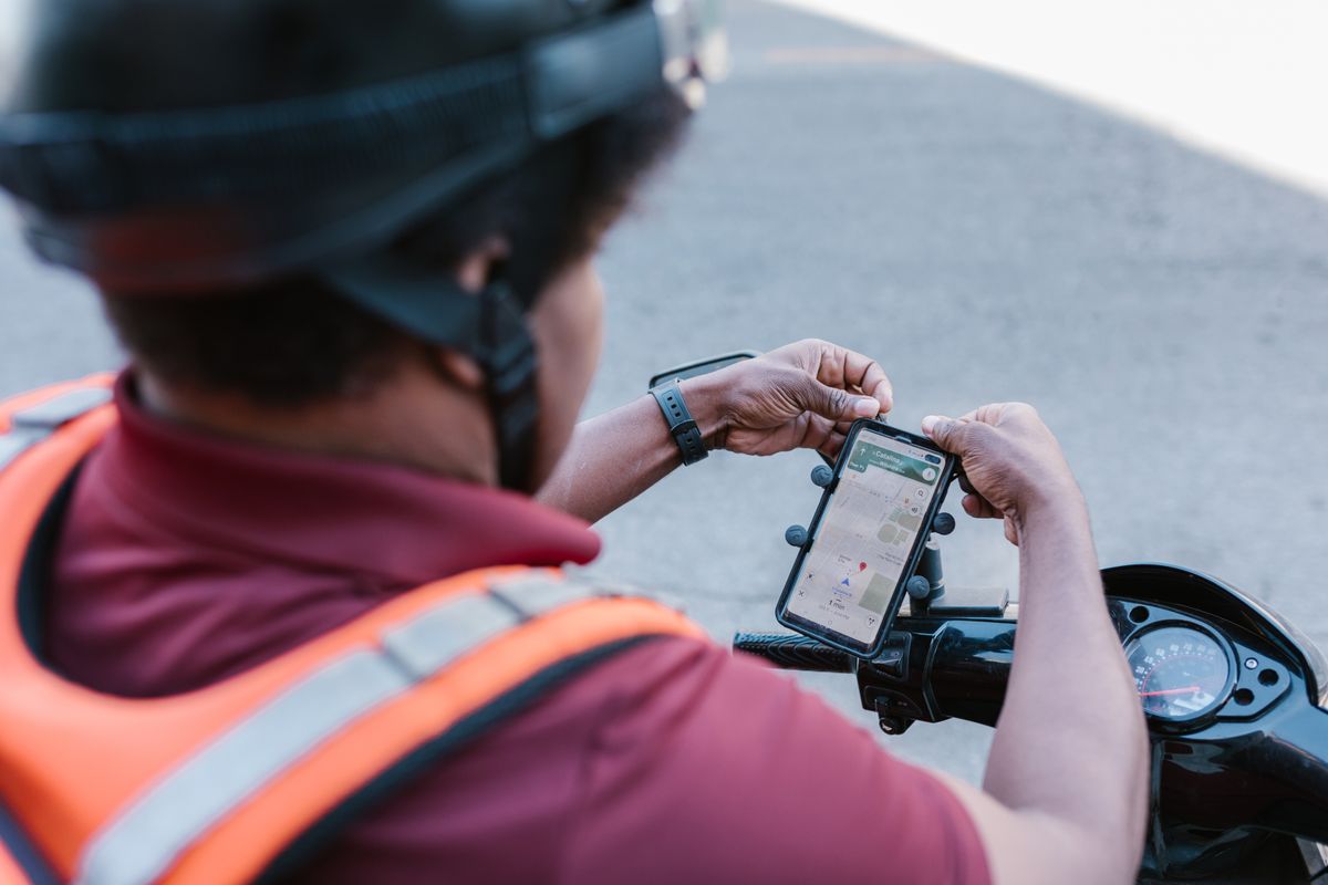Delivery rider checking a smartphone on a motorbike